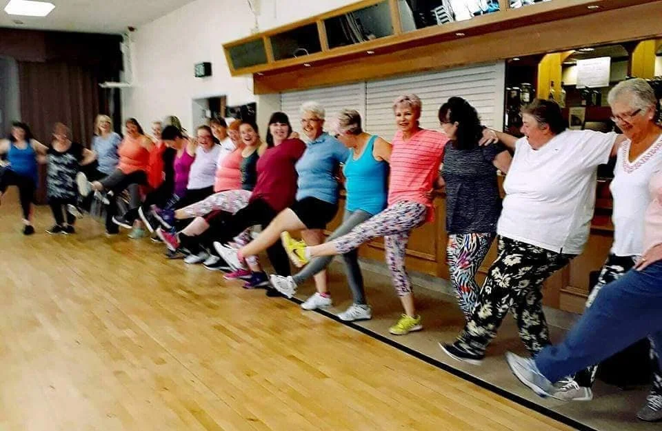 Bumba Fitness class mid-routine, arms in the air