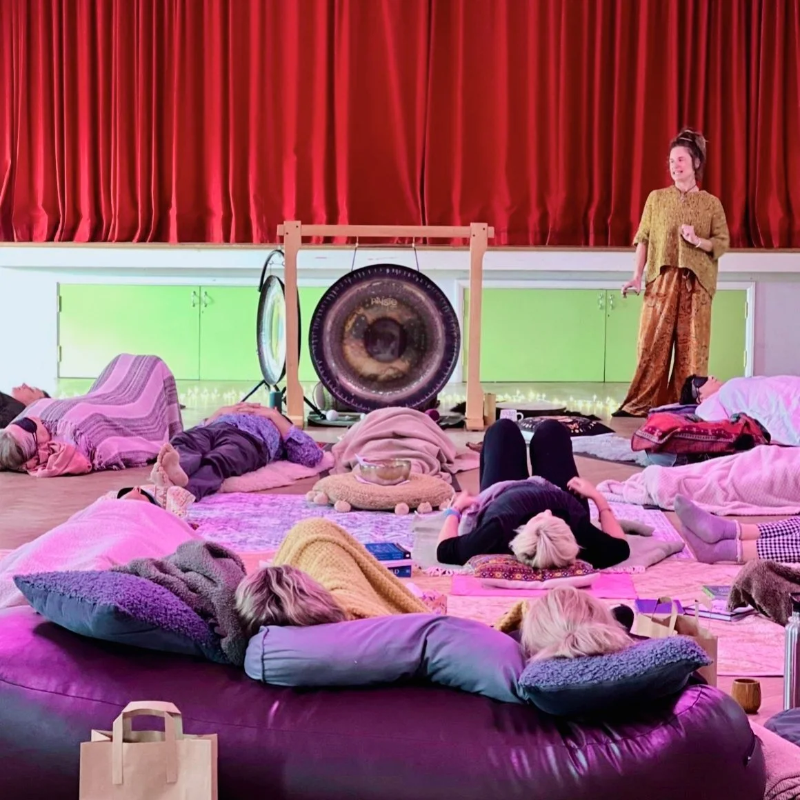 Gong bath in a candlelit hall with guests resting on cushions