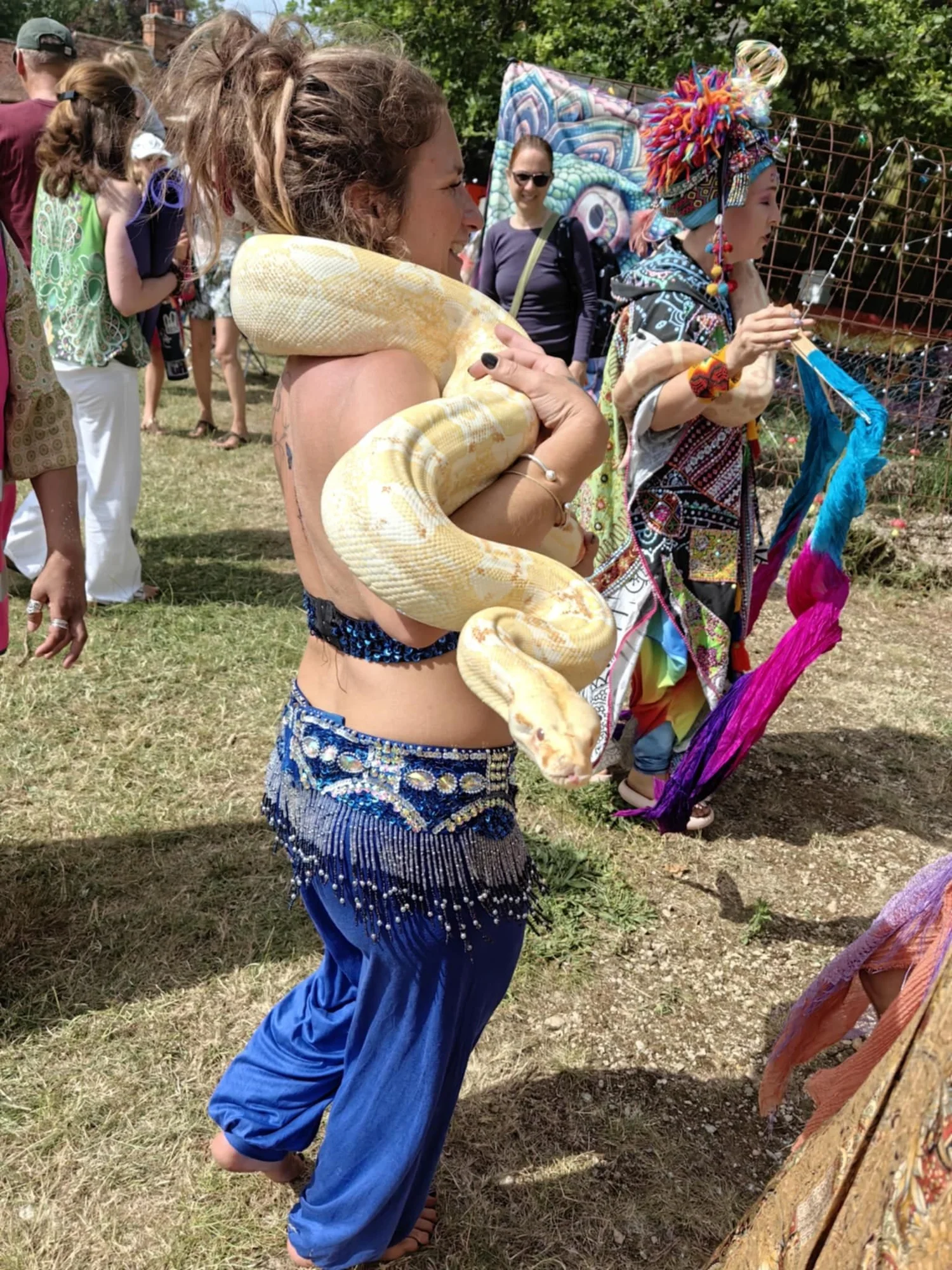 Saz in belly dance costume at a festival with an albino python around her shoulders
